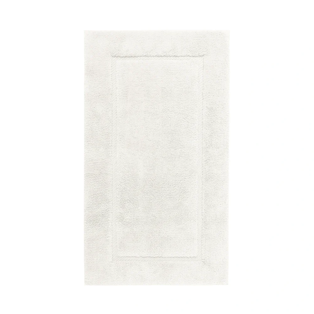 Ovanifrån-vy av en utsträckt Egoist badrumsmatta i färgtonen Snow (offwhite - elfenbensvit). Detaljerat studiophoto som framhäver den mjuka strukturen hos den exklusiva GIZA-bomullen.